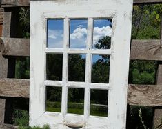 an old window is reflecting the sky and clouds in it's glass pane