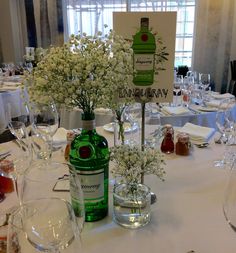 the table is set with wine glasses, bottles and vases filled with baby's breath flowers