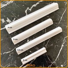 three different sizes and shapes of white plastic tubes on a black marble counter top with measurements for each tube