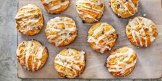 a wooden cutting board topped with muffins covered in icing