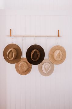 three hats are hanging on a wall with two wooden pegs and one hat hangs from the wall