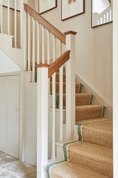 there are pictures hanging on the wall above the stairs in this house, along with carpeted flooring