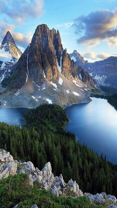 the mountains are covered in snow and green trees, with blue water surrounded by rocks