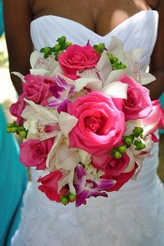 a bride holding a bouquet of pink roses and orchids in her wedding day dress