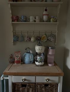 a coffee maker on top of a wooden counter next to baskets and cups in front of it