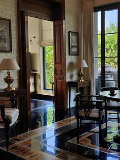 a living room filled with furniture next to two large windows and a table in front of them