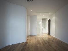 an empty room with wooden floors and white walls, in the middle of a house