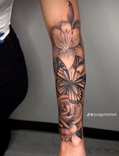 a woman's leg with a butterfly and flower tattoo on the left side of her arm