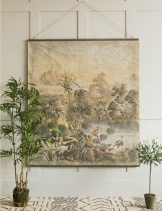 a painting hanging on the wall next to two potted plants