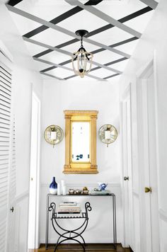 a hallway with white walls and wood flooring has a gold framed mirror on the wall