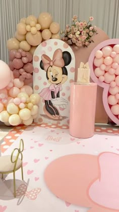 a table topped with lots of balloons and minnie mouse decorations on top of pink polka dot covered tables