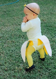 a baby dressed as a banana is standing in the grass