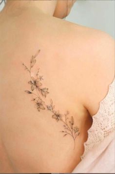 the back of a woman's shoulder with small flowers on her left side,