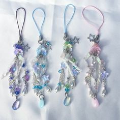 three necklaces with charms hanging from them on a white cloth covered tablecloth in the shape of stars