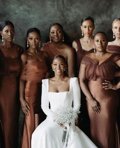 a group of women standing next to each other in formal dresses and gowns with one woman holding a bouquet