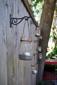 an old fashioned mason jar hanging on the side of a wooden fence with several jars attached to it