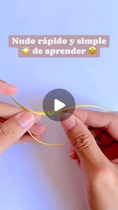 two hands are doing something with yellow thread