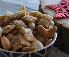 a bowl filled with cereal and nuts on top of a table next to a piece of wood