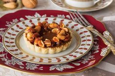 a plate topped with a pastry covered in nuts next to a cup and saucer