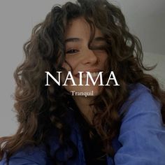 a woman with long curly hair smiling and wearing a blue jacket that says namma