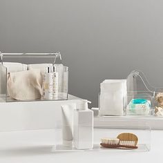 two clear acrylic containers with toothbrushes and soaps