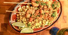 shrimp and corn stir fry on a red plate with chopsticks next to it