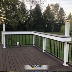 a wooden deck with black iron railings and white posts