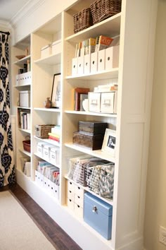 a white bookcase filled with lots of books next to a wall covered in boxes