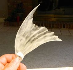 a person holding up a piece of paper that looks like a bird's wing