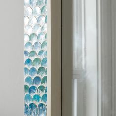 a close up of a glass window with water droplets on it and a curtain in the background