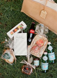 the contents of a picnic bag are laid out on the grass, including beer and snacks