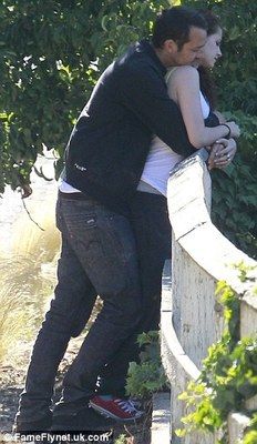 a man and woman leaning against a stone wall with their arms around each other as they hug