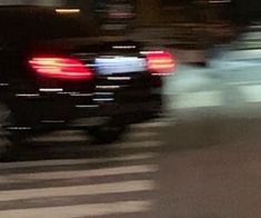 a blurry photo of a car driving down the street at night with its tail lights on