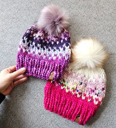 two knitted hats with pom - poms on the top