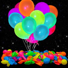 a bunch of balloons floating in the air over a pile of colorful confetti