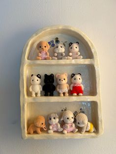 there are many small toy animals on the shelf in this wall hanging display case that is made out of clay