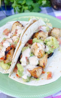 two tacos with chicken and avocado on a green plate