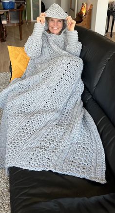 a woman sitting on top of a couch covered in a crocheted afghan blanket