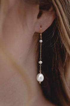 a close up of a woman's ear wearing gold and white earrings with pearls