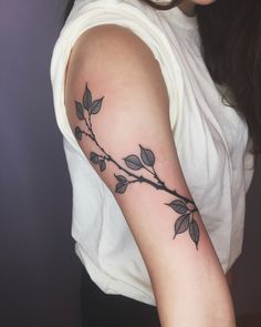 a woman's arm with a branch tattoo on the left side of her arm