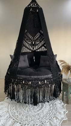 a black bed with fringes and pillows on top of a white doily rug