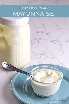 homemade mayonnaise in a glass bowl on a blue plate with a spoon next to it