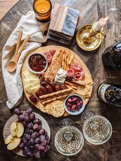 an assortment of cheeses, crackers and grapes on a wooden table