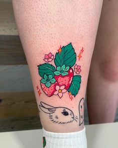 a woman's leg with strawberrys and bunny on it, while she is wearing white socks