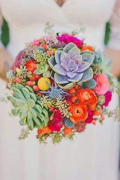 an image of a bride holding a bouquet on her wedding day with succulents and flowers