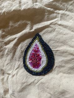 a beaded brooch with a pink and blue tear on it's side