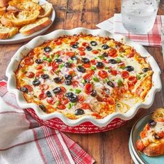 a casserole dish with olives, peppers and cheese in it on a wooden table