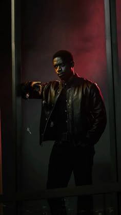 a man standing in front of a mirror with his hands on his hips and wearing a leather jacket