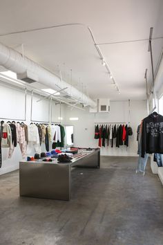 the inside of a clothing store with clothes on racks