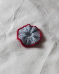 a piece of yarn sitting on top of a white cloth covered in red and gray dye